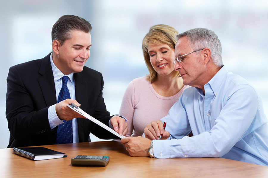 Financial advisor discussing paperwork with senior couple at desk.