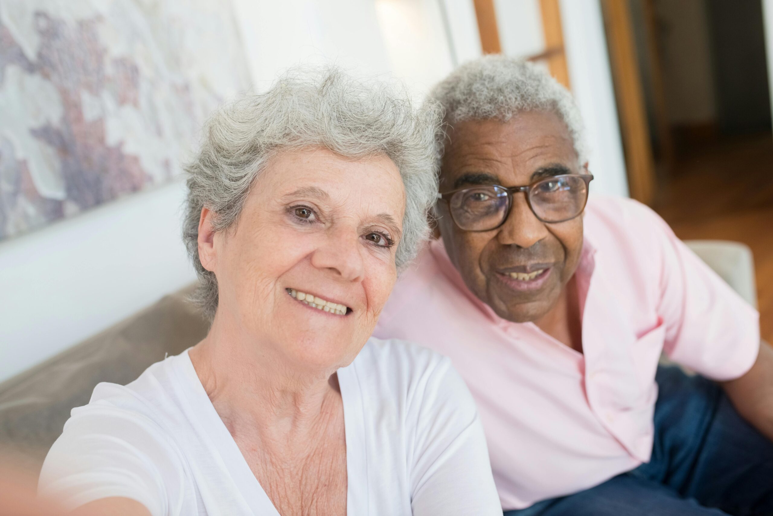 Smiling elderly couple taking a cheerful selfie at home.