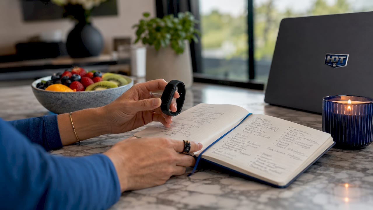 Hands with fitness tracker and wellness journal on table